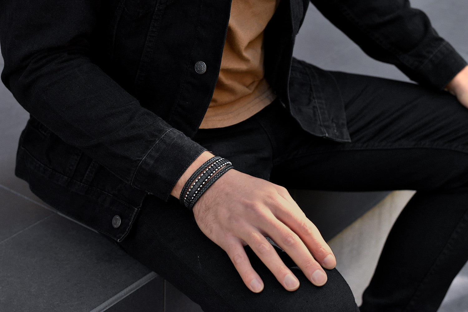 Stylish man in a casual black jeans outfit wears a Rianrix leather bracelet